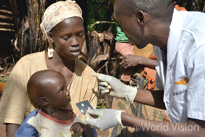 말라리아를 앓고 있는 아이 디빈(Divin)은 엄마와 함께 진단을 받고 치료약에 대한 설명을 듣고 있습니다 (사진출처: 월드비전)